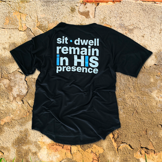 Black ABiDE t-shirt with sit dwell reamin in HIS presence text on a stone surface