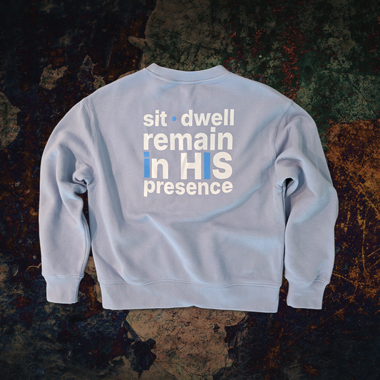 Light blue ABiDE sweatshirt with sit dwell remain in HIS presence on the back against a textured dark background