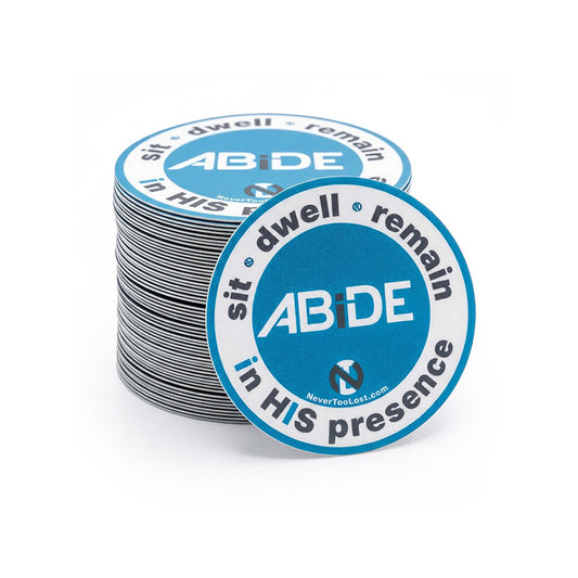 A stack of circular blue and white stickers with the text 'sit * dwell * remain in HIS presence' and 'ABiDE' in the center, with one sticker placed in front of the stack on a white background.