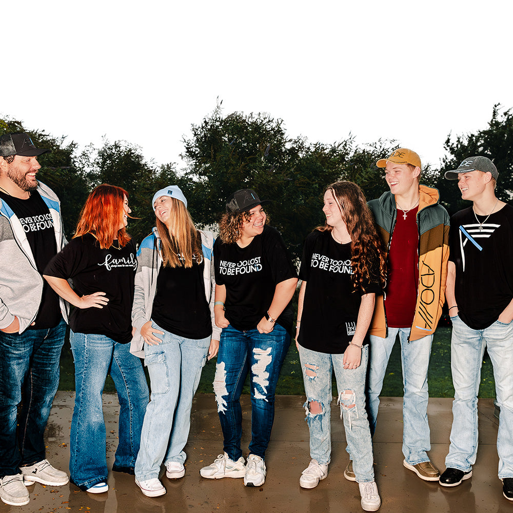 Christian Family and friends gathering, laughing wearing Never Too Lost Christian Apparel Never Too Lost Bamboo Tees, Adonai and I AM zip-up hoodies ABIDE trucker and dad hats and family bamboo tees