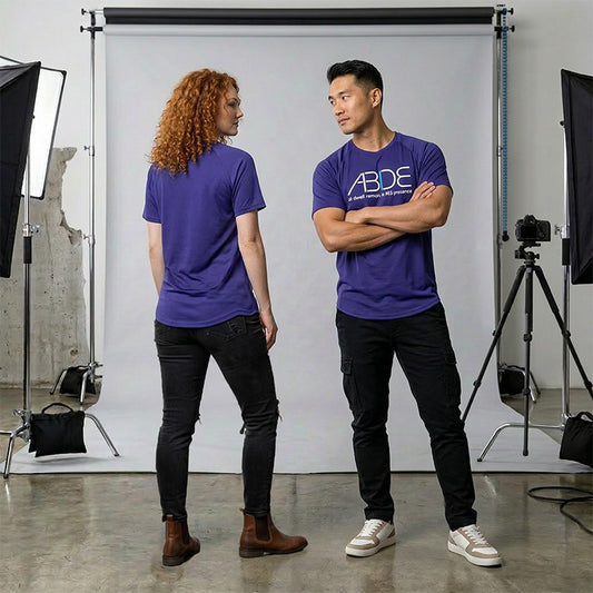 Two people wearing purple bamboo ABIDE shirts standing in a photo studio with photography equipment.