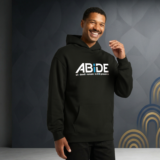 Man wearing a black hoodie with 'ABiDE | sit - dwell - remain in HIS presence' logo against a dark background