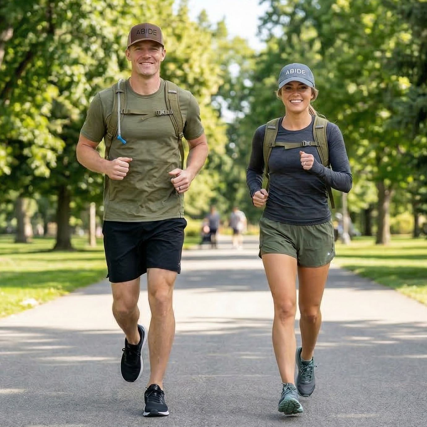 Two people wearing ABiDE hats walking outdoors on a path with trees in the background