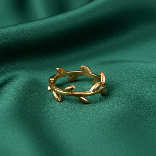 Gold ring with olive branch and leaf design on green satin cloth