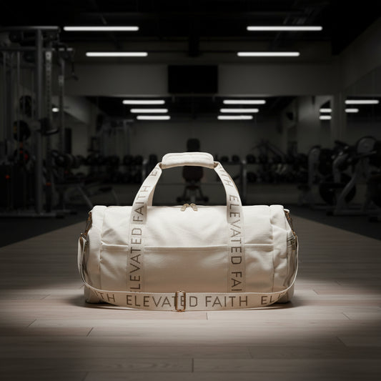 Beige duffel bag with 'Elevated Faith' branding on gym floor
