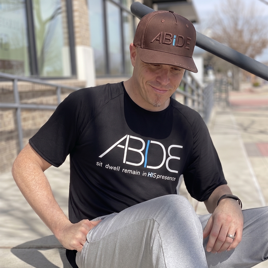 Man Wearing abide clothing black bamboo tee and abide brown trucker hat