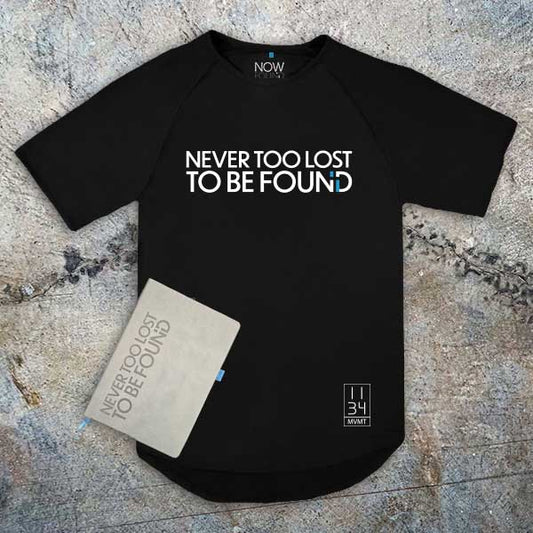 Black t-shirt and Christian Journal with 'Never Too Lost To Be Found' text on a textured surface