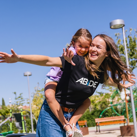 Woman and child playing in a park with 'ABIDE' shirt
