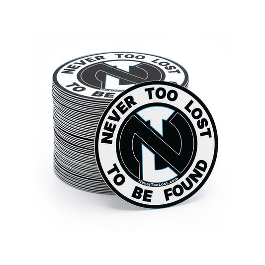 A stack of round black and white stickers featuring the text 'NEVER TOO LOST TO BE FOUND' and a stylized 'NTL' logo, shown on a clean white background.