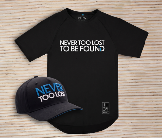 Black bamboo t-shirt and cap with 'Never Too Lost To Be Found' text on a wooden surface