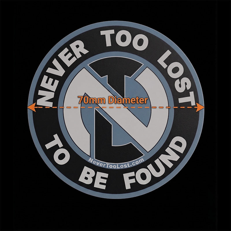 A circular black and gray sticker with a white, black, and blue Never Too Lost logo in the center, bordered by the words 'NEVER TOO LOST TO BE FOUND' in white. An orange dashed line across the center reads '70mm Diameter'.