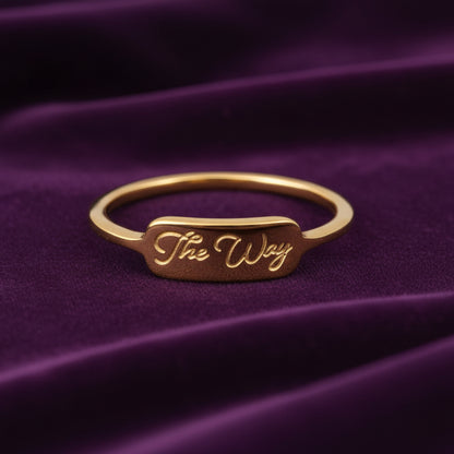 Gold ring with 'The Way' engraving on purple velvet