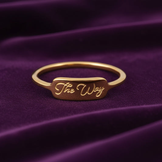 Gold ring with 'The Way' engraving on purple velvet