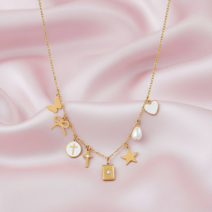 Gold necklace with various Christian themed charms on a light pink satin cloth