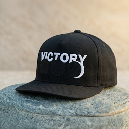 Black cap with 'VICTORY' logo on a stone surface