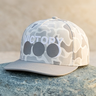 Light gray Camouflage baseball cap with 'VICTORY' text on a stone surface