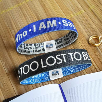 Never Too Lost and I Am Who I AM Says I Am Wristbands on bamboo next to journal