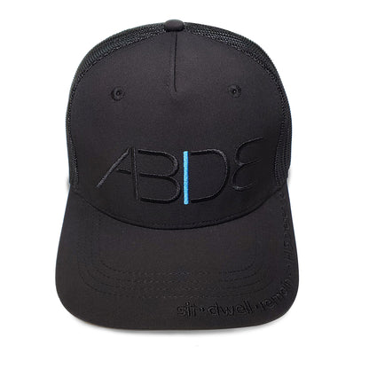 black abide blackout trucker hat front view with sit dwell remain in his presence on bill